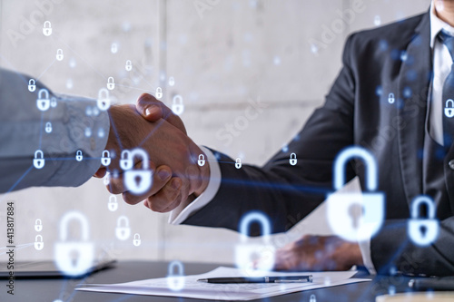 Handshake of two businessmen who enters into the contract to protect cyber security of international company. Padlock Hologram icons over the table with documents.