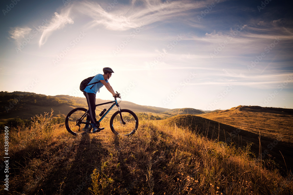 Male athlete on bicycle in grassy field against cloudy sky Male athlete on bicycle in grassy field against cloudy sky