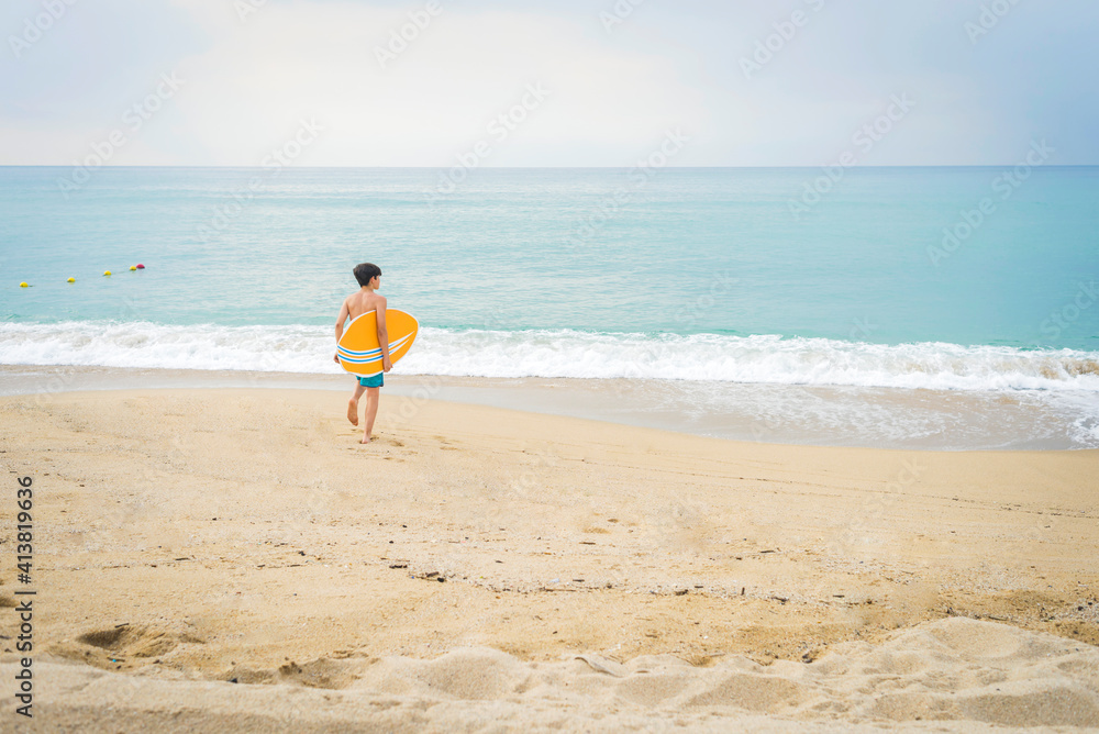 young surfer walking towards the water young surfer walking towards the water