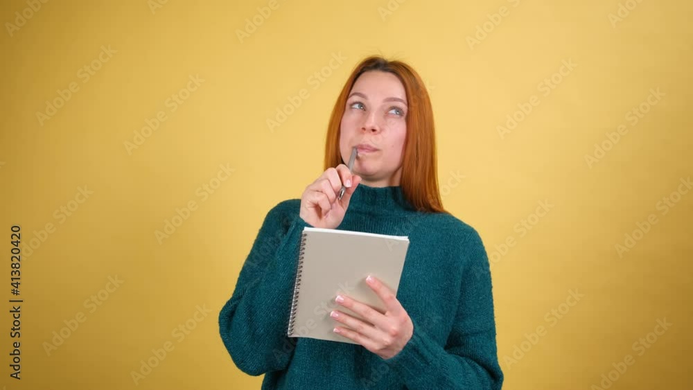 Thoughtful creative young woman in green sweater thinking over future business plan, taking notes in paper notebook, writing creative idea and smiling inspired happy. indoor isolated Thoughtful creative young woman in green sweater thinking over future business plan, taking notes in paper notebook, writing creative idea and smiling inspired happy. indoor isolated