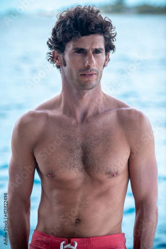 Portrait of handsome man, shirtless surfer with white teeth smile and blue ocean on background in Maldives © Lila Koan