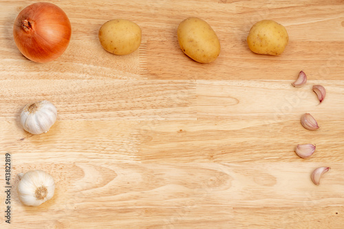 onion and potatoes on wooden table with copy space