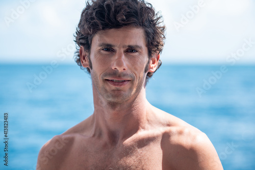 Portrait of handsome man, shirtless surfer with and blue ocean on background in Maldives © Lila Koan