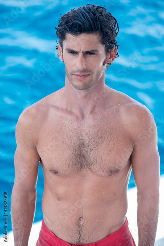 Portrait of handsome man, shirtless surfer and blue ocean on background in Maldives