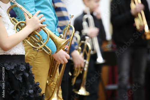 A group of children students of young musicians boys and girls with musical instruments trumpet and saxophone at a music lesson in the classroom.Blurred background with focus in the foreground