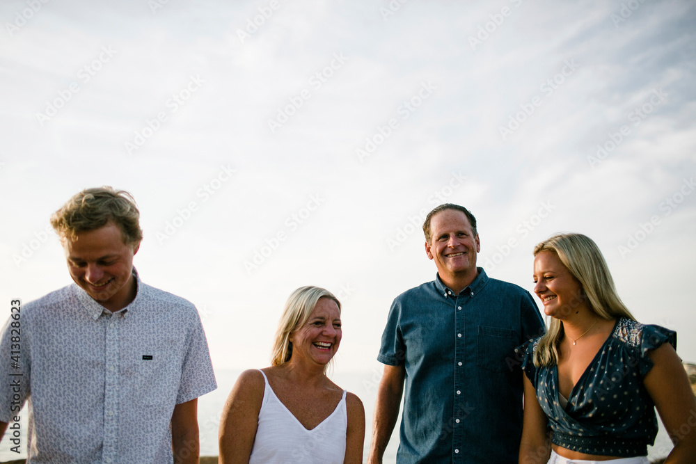 Happy family standing at beach against sky during sunset Happy family standing at beach against sky during sunset
