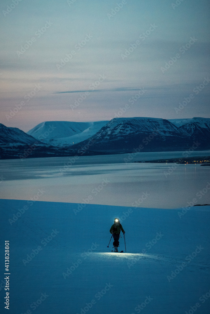 A man backcountry skiing at sunrise with mountains and ocean A man backcountry skiing at sunrise with mountains and ocean
