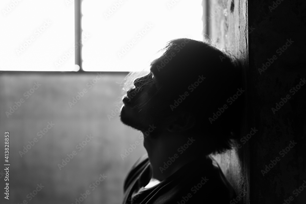 Unhappy young man get hopeless and depressed Asian guy stay alone in dark room Feel loneliness Sadness men is depression illness Health care Mental health concept Selective focus black and white photo