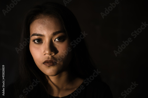 Portrait charming beautiful confident woman in dark room. Attractive beautiful asian girl look at camera. Glamour woman get determined, confidence. She has beautiful face. copy space, black background