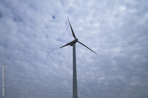 one wind power turbine in the center, white cloud sky background 