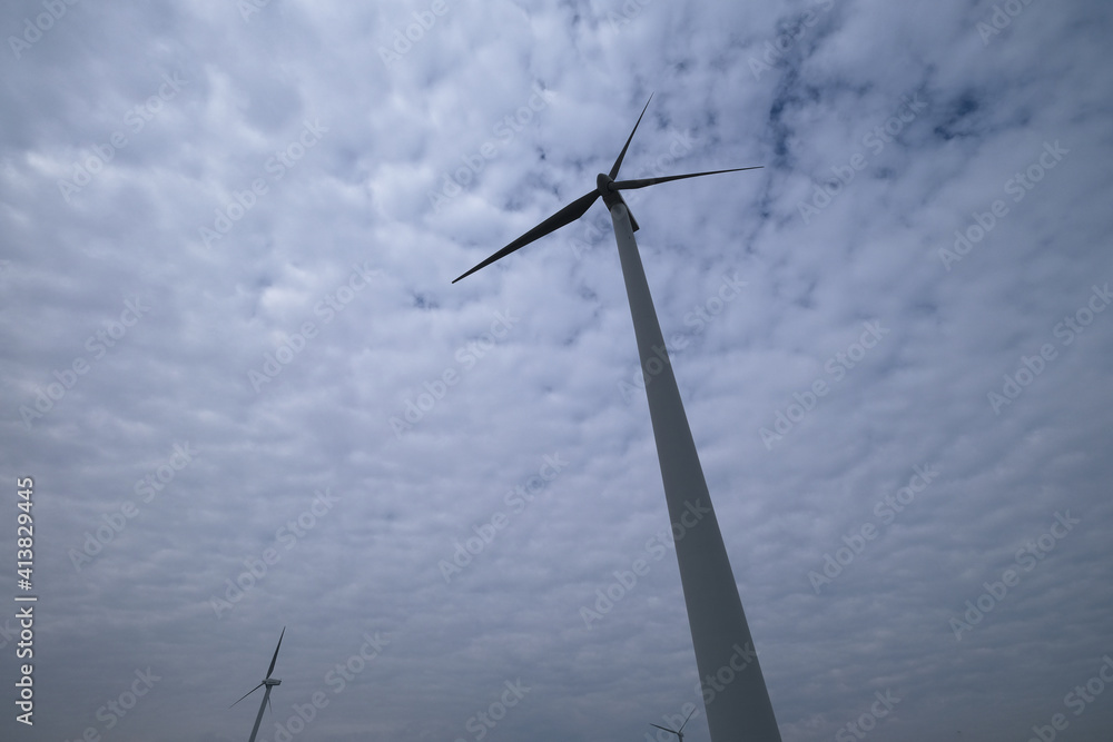 Fototapeta premium low angle and wide angle view of wind power turbine with white cloud sky background 
