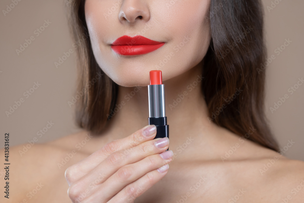 Lower part of womans face and red lipstick in hand Lower part of womans face and red lipstick in hand