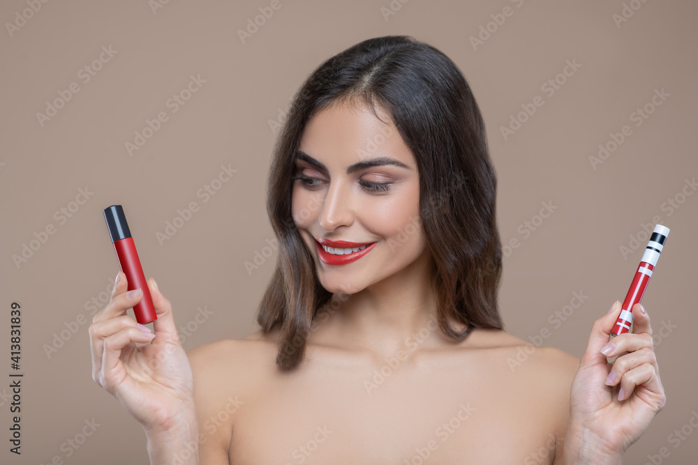 Woman holding two shades of red lip gloss Woman holding two shades of red lip gloss