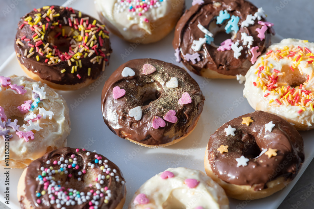 Donuts mit Schokolade und Streusel un verschiedenen Formen, Herzen, Sternen und Einhörnern auf einem weißen Teller. Donuts mit Schokolade und Streusel un verschiedenen Formen, Herzen, Sternen und Einhörnern auf einem weißen Teller.