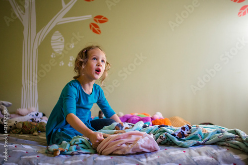 a smiling girl plays alone in her bedroom in sunlight photo