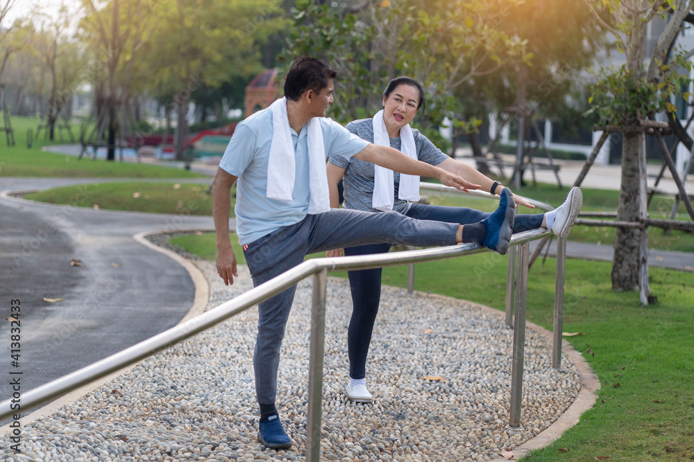 Fototapeta premium senior couple finished their run, had a towel over their necks and stretched their legs on a bra in the park in the morning.
