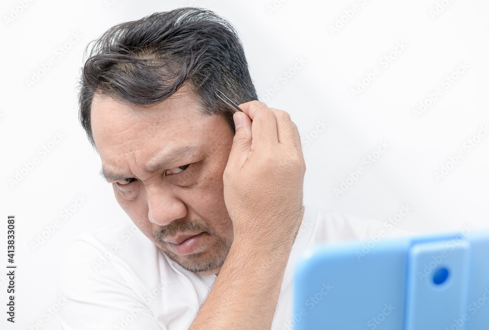 Asian middle man using tweezers to pluck his gray hair isolated Asian middle man using tweezers to pluck his gray hair isolated