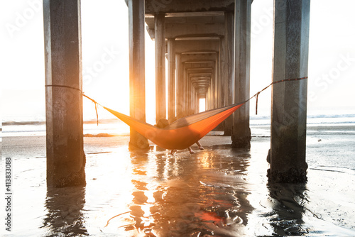 Girls in a Hammock Under a Pier By the Ocean at Sunset in Southe photo