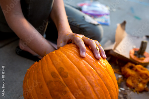 Hand reaches into pumpkin to remove seeds photo