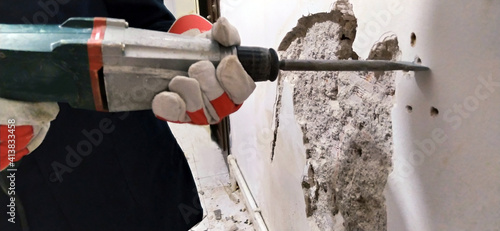 Installer stabs hole with Hilti rotary hammer in the wall on the construction site