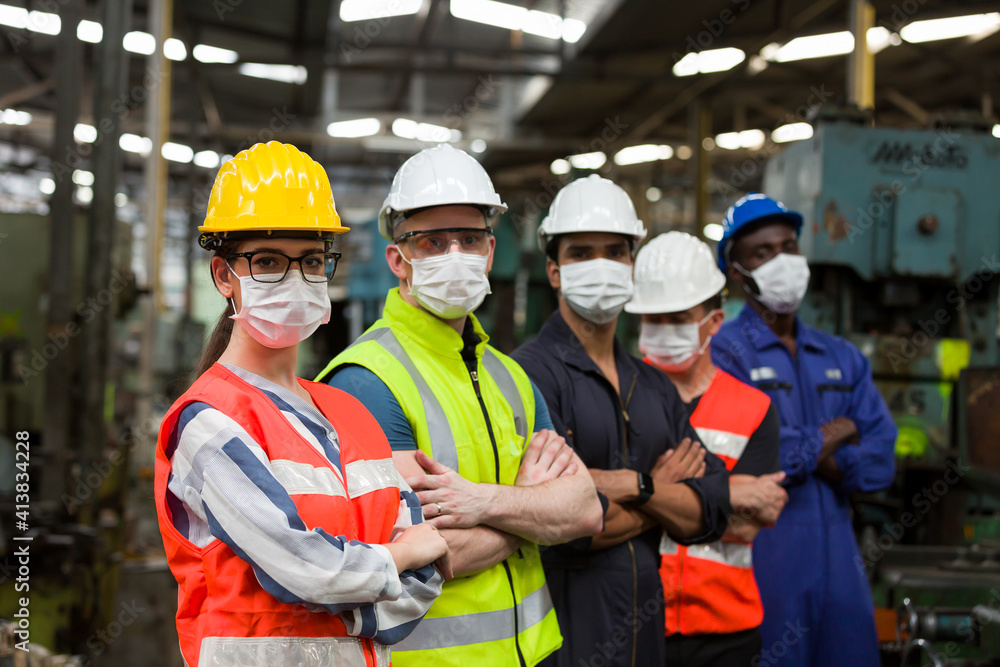 Group of diversity factory worker wearing face mask working at factory. Team of technician worker in safety uniform, helmet and face mask in the industry factory. Industry and health care concept Group of diversity factory worker wearing face mask working at factory. Team of technician worker in safety uniform, helmet and face mask in the industry factory. Industry and health care concept