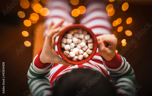 Overhead shot of child holding cup of hot cocoa with mashmallows. photo