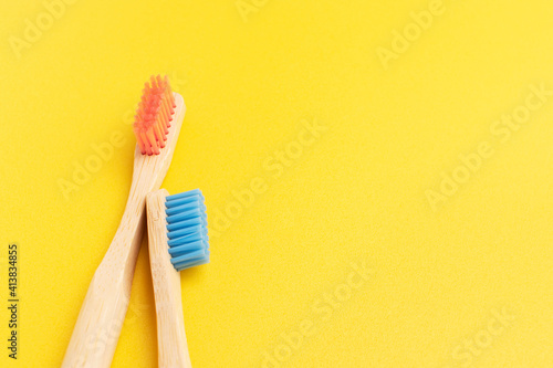 Two bamboo toothbrushes. Eco friendly equipment for personal oral hygiene. Yellow background  top view.