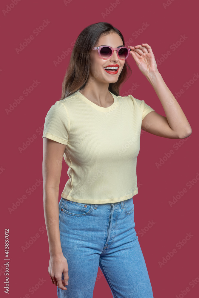 Woman in jeans and tshirt straightening glasses Woman in jeans and tshirt straightening glasses