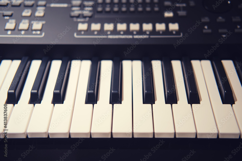 Fototapeta premium Black synthesizer with white keys, modern electronic piano with sliders and buttons for recording music