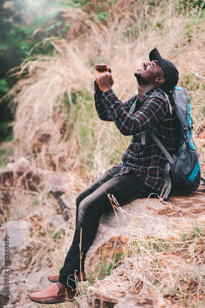 Success african man traveler sitting on the cliff with backpack.16:9 style Success african man traveler sitting on the cliff with backpack.16:9 style