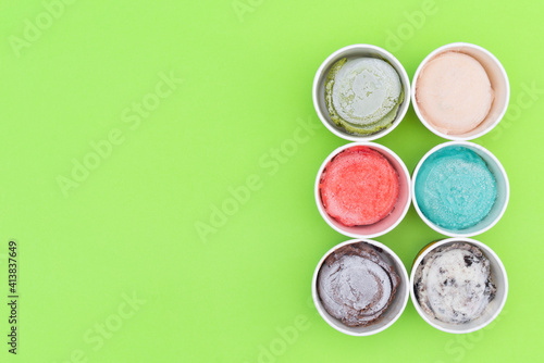 Top view of Ice cream flavors in cup and topping, sweet and dessert on green table background, flat lay, sweet food concept