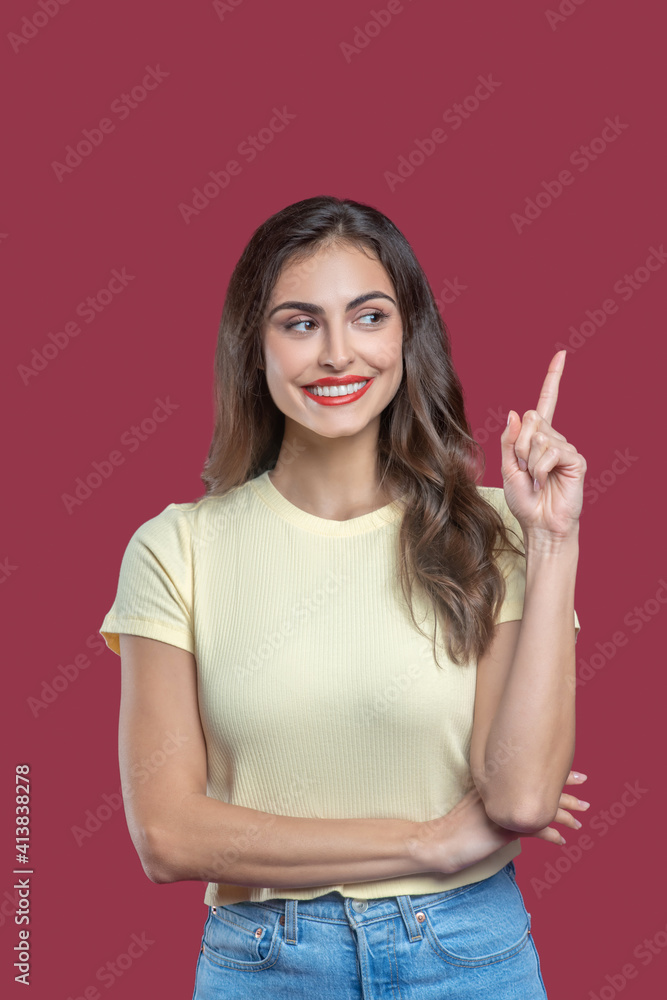 Smiling woman pointing finger up looking to side Smiling woman pointing finger up looking to side