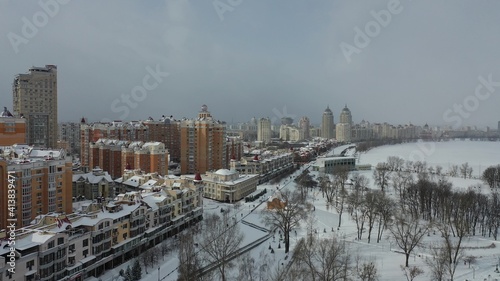 Europe, Kiev, Ukraine - February 2021: Aerial view of Obolonskaya embankment. Snowy real estate. Winter view of the city.