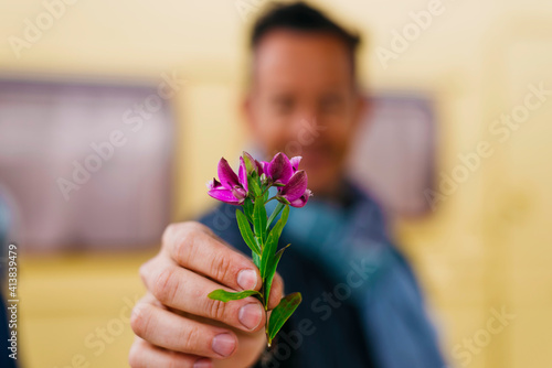 Man out of focus holding a flower ( cllose up ) photo