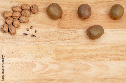 Top view of walnuts, kiwis and pine nuts with copyspace on a wooden table