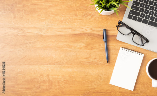 Flat lay of Office desk with laptop, and blank notepad with a coffee cup on wood table, copy space, top view