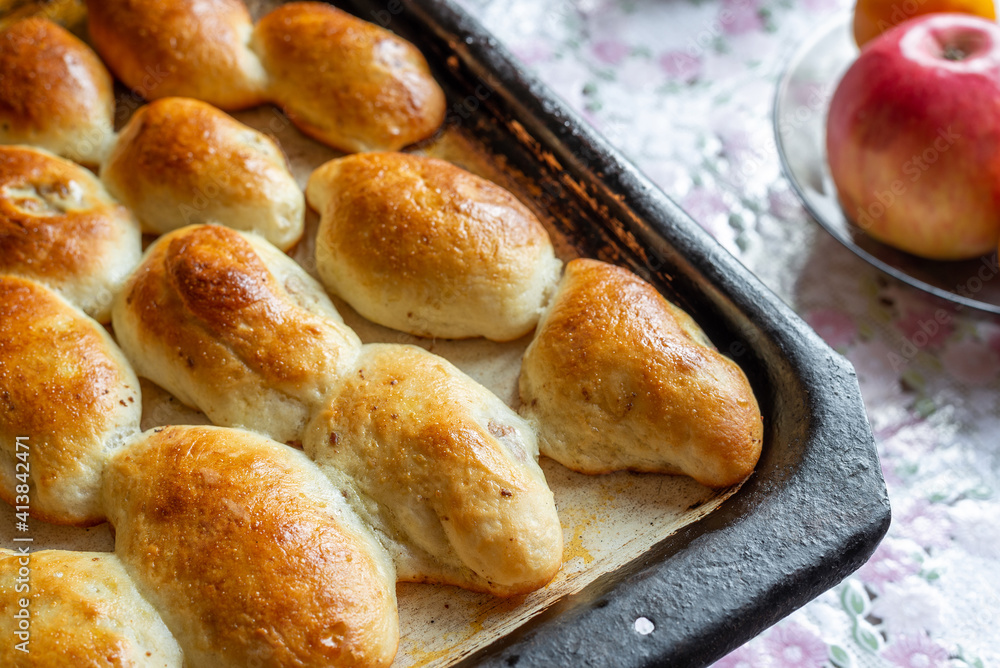 Baked homemade pies with apple on the baking sheet