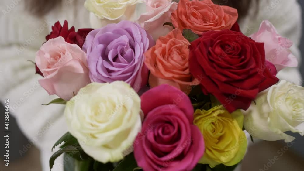 Close up colorful roses bouquet from fresh flowers in female hands. Woman hands in white knitted sweater holding roses bouquet Close up colorful roses bouquet from fresh flowers in female hands. Woman hands in white knitted sweater holding roses bouquet