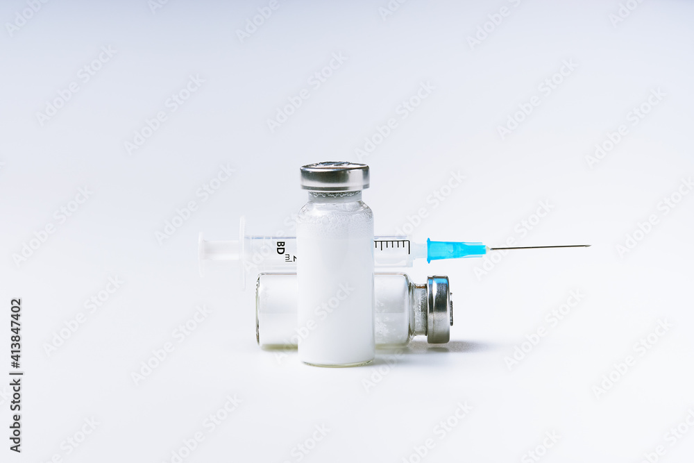 Close up glass vial with flu vaccine and syringe with needle. The concept of vaccination or preventive treatment of injection diseases. Close up glass vial with flu vaccine and syringe with needle. The concept of vaccination or preventive treatment of injection diseases.