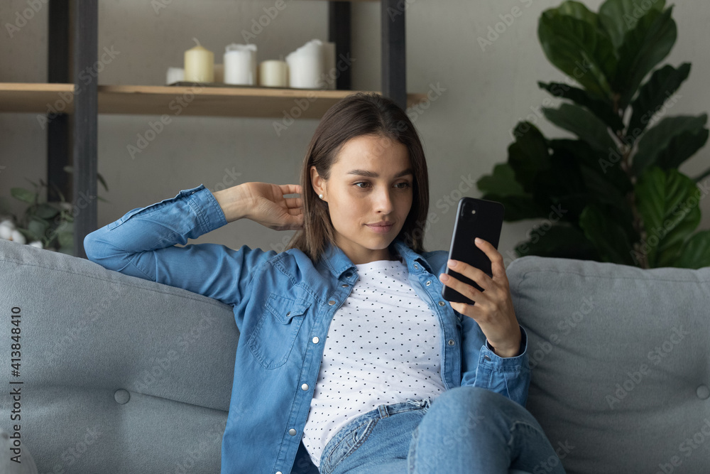 Φωτογραφία Pretty female student sit on couch hold stylish smartphone pose for cute selfie to send friend or post at social network