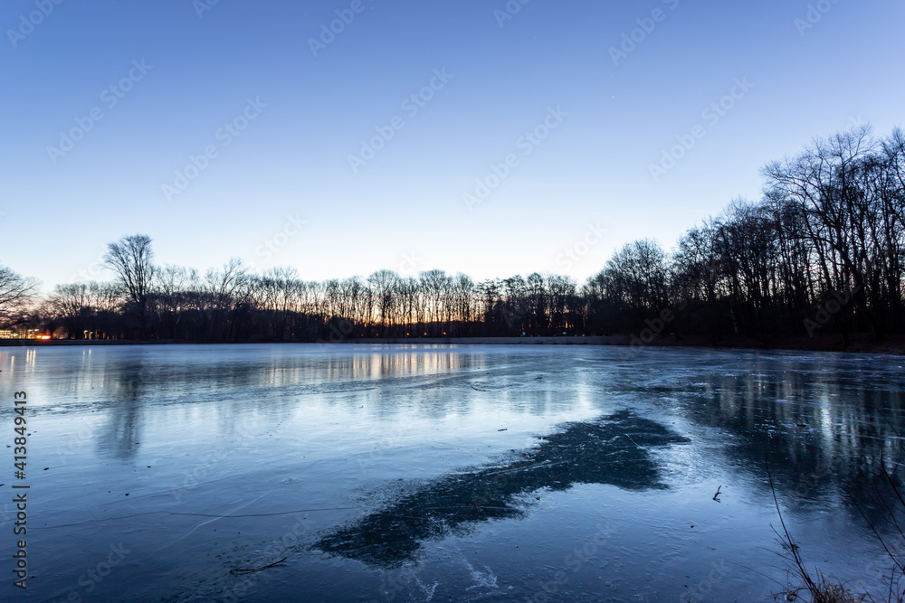 frozen ice surface of Decksteiner Weiher lake in Cologne at sunrise