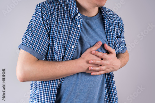 Heart attack, diseases of the cardiovascular system, man with chest pain on gray background photo