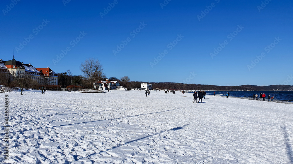 People are walking on a snow-covered beach in Sopot on a beautiful sunny day, Poland People are walking on a snow-covered beach in Sopot on a beautiful sunny day, Poland