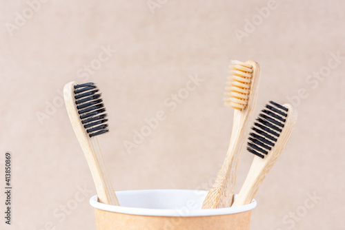 Eco friendly bamboo toothbrushes in cup on brown background. Zero waste concept