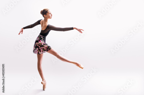 Ballerina in black pointes posing in graceful pose on white background