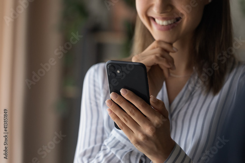 Close up cropped shot of smiling confident young woman enjoy using modern smartphone. Happy teen female read message from cell screen watch video in app search data online in internet social network