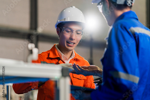 Male Asian engineer professional  having a discussion standing concult cnc machine in the factory ,two asian coworker brainstorm  explaining and solves the process of the cnc operate machine photo