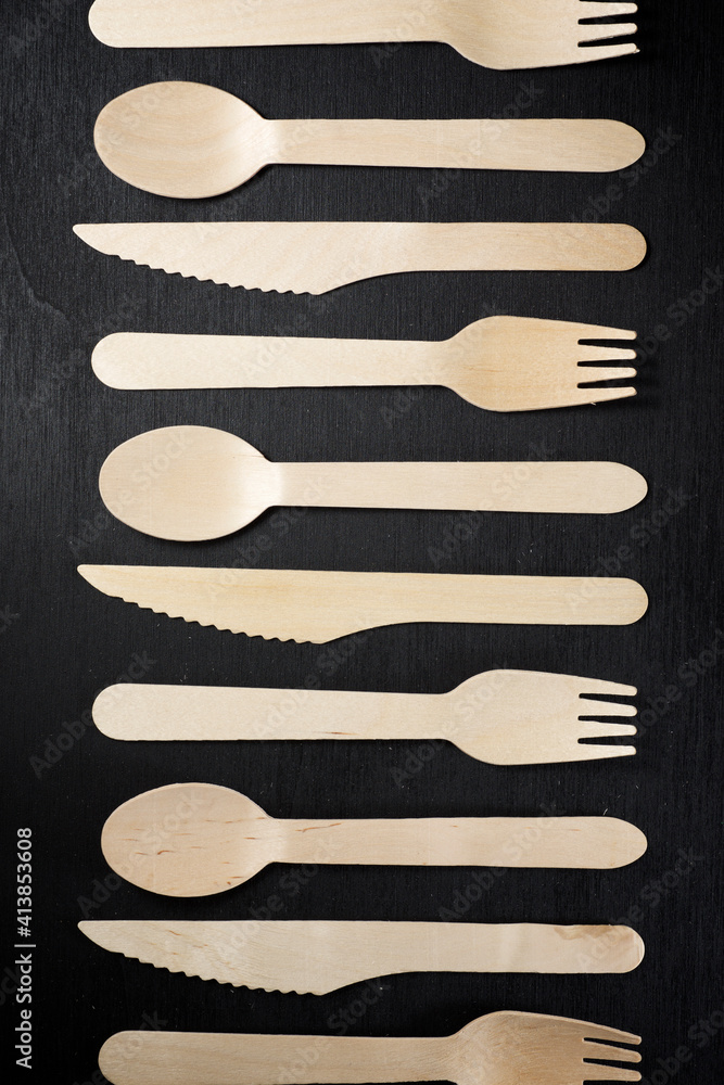 Disposable wooden cutlery on a black table. Disposable wooden cutlery on a black table.