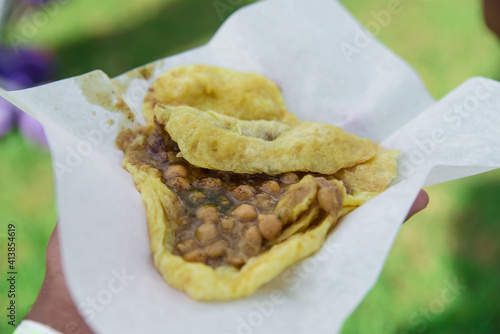 Port of Spain, Trinidad and Tobago - August 9, 2019: A freshly served hand of doubles, given to a foodie at a street food market.