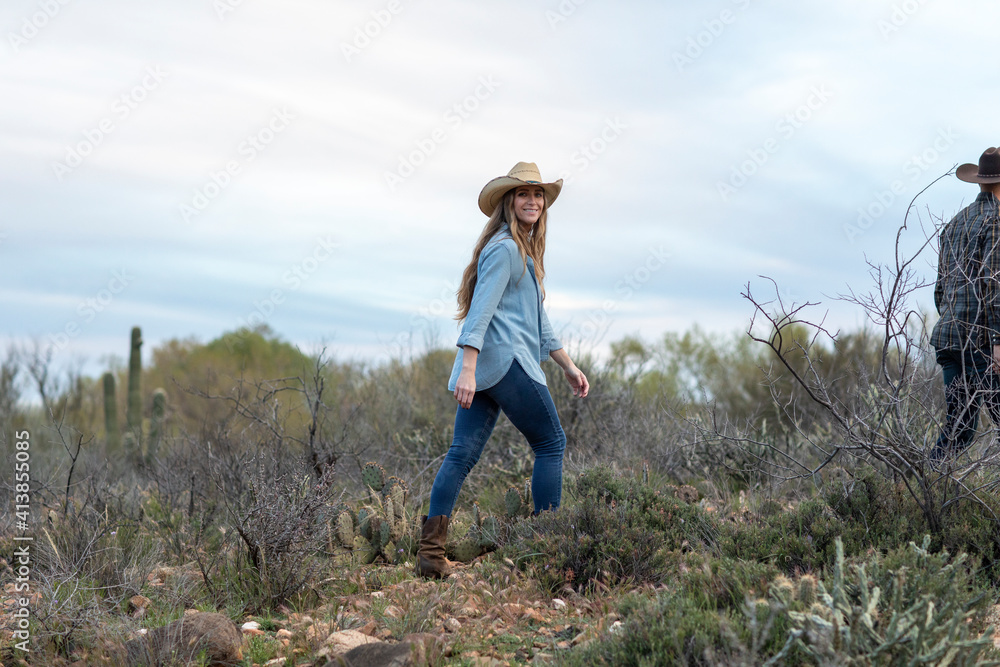 Western wear young woman walking in desert ranch Western wear young woman walking in desert ranch